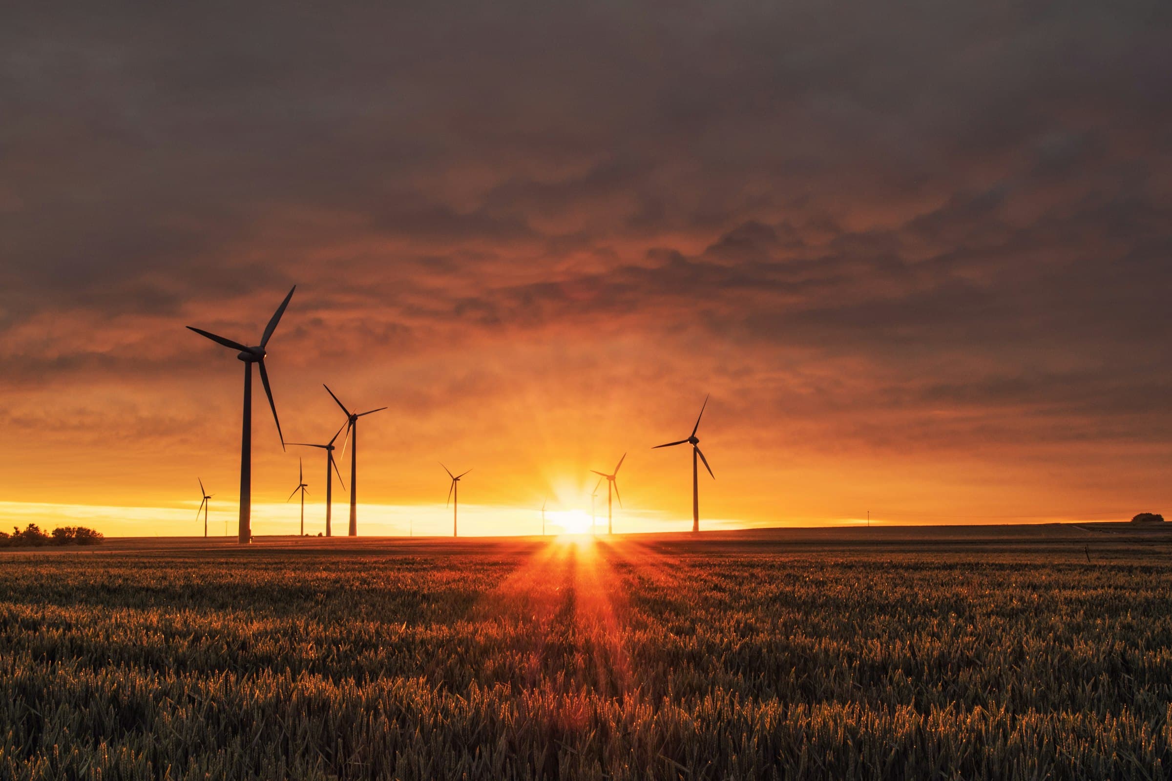 Wind turbines silhouetted against a vivid sunset